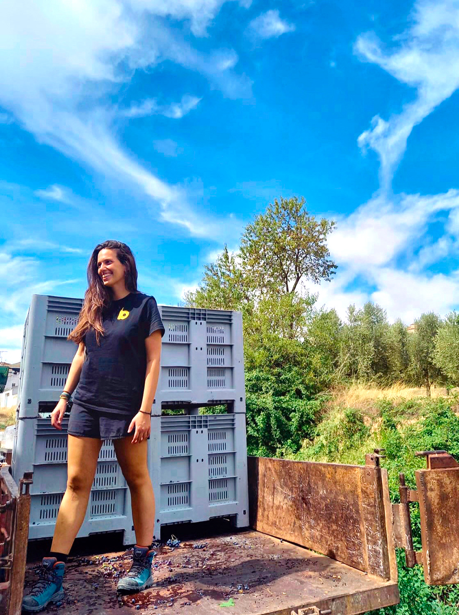 Fotografia de Gemma Miró pujada al remolc, al darrere es veuen 4 caixes preparades per carregar el raïm.